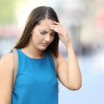 Woman suffering headache on the street